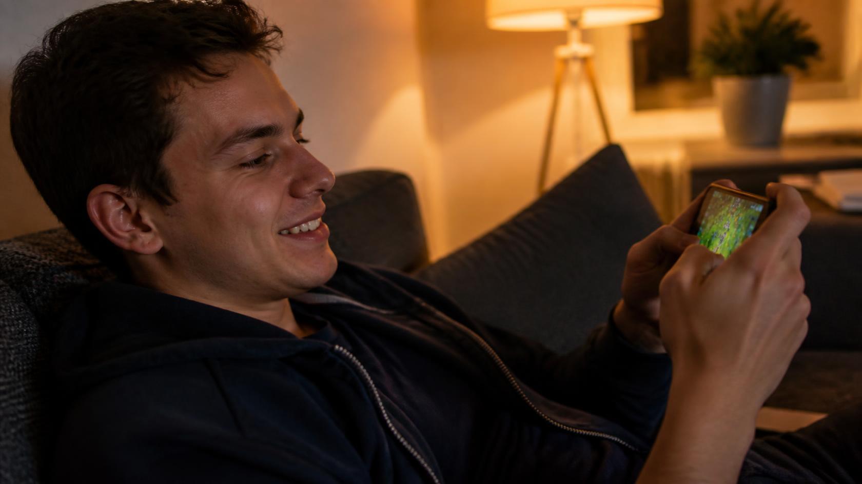 A relaxed person enjoying mobile casino-style games at home during MZPlay downtime.